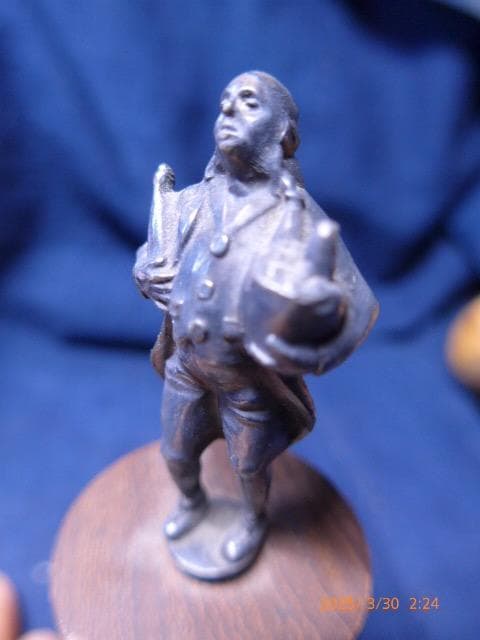 銀の無垢でしょうか？小さい割には作りの良い彫刻です。木製の台にセットされています